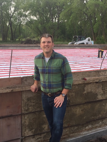 Man posing for a picture standing next to a wall.