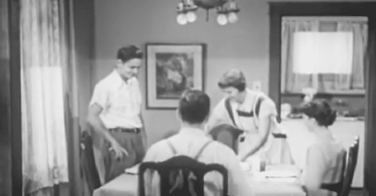 A black and white photo of teens at a table.