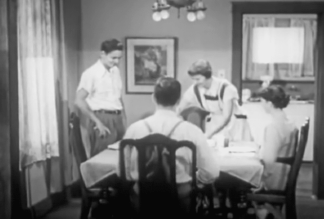 A black and white photo of teens at a table.