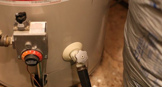 A hot water heater with a hose attached for flushing.