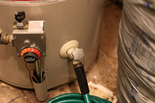 A hot water heater with a hose attached for flushing.