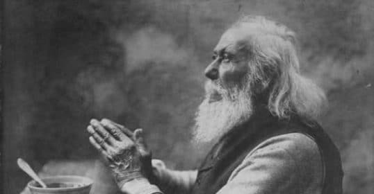 An old photograph of a man praying in black and white.