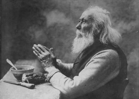 An old photograph of a man praying in black and white.