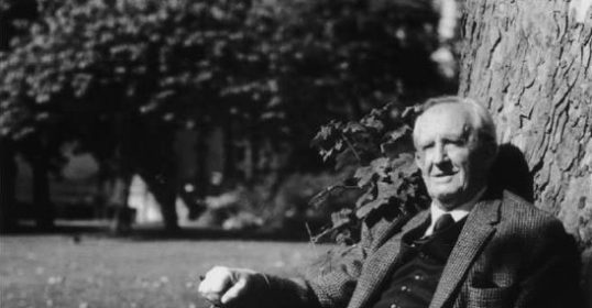 A man in a suit sitting under a tree, embracing the Cult of Travel.