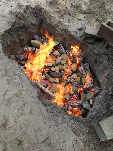 Burning a fire in digging area with rocks and coals.