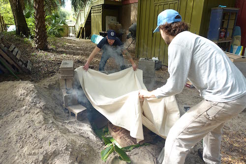  Los hombres colocan lienzos sobre todo el imu superponiendo los bordes.