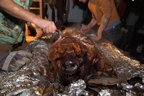 Man cutting a piece of pig meat with knife.