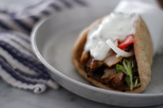 An authentic Greek plate with gyro meat and vegetables on a pita.