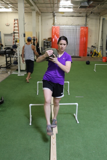 woman carrying sandbag while balancing on 2x4 movnat workshop