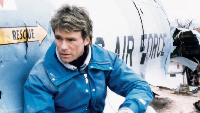A man in a blue jacket expertly leaning against a plane, showcasing his urban survival skills.