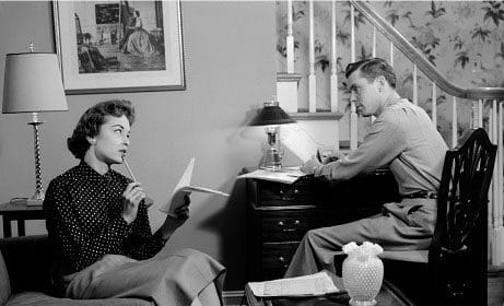 Black and white photo of a man and woman sitting in a living room during their weekly marriage meeting.