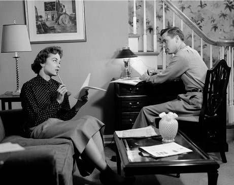 Black and white photo of a man and woman sitting in a living room during their weekly marriage meeting.