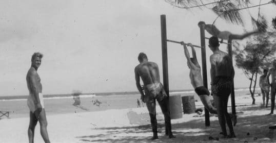 A group of men staying fit on a beach.