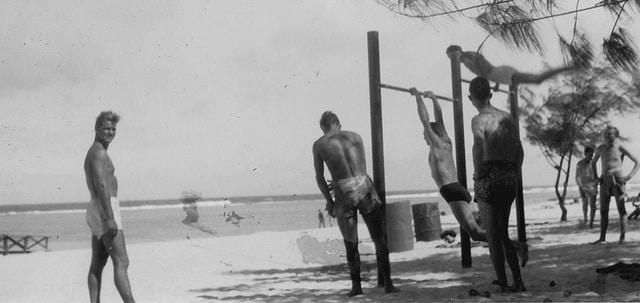 A group of men staying fit on a beach.