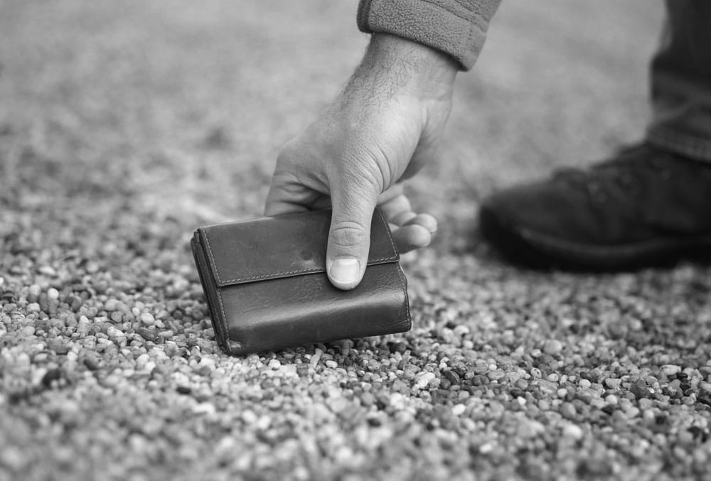 A man putting a wallet on the ground in a black and white photo.