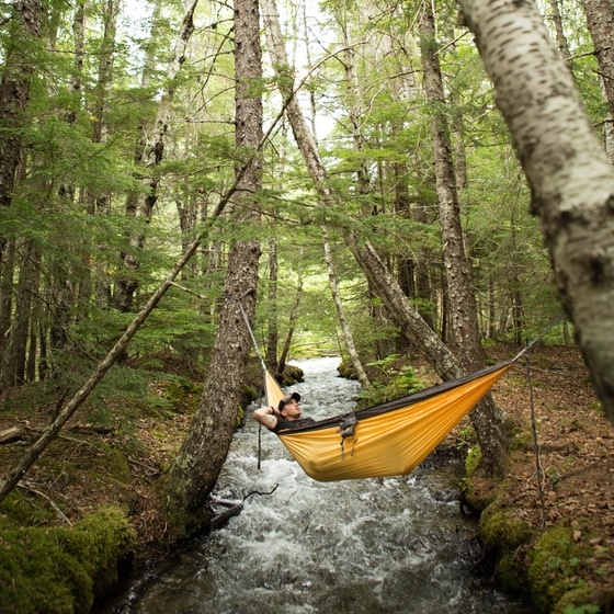 Hammock camping man relaxing in hammock over river.