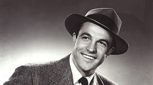 A black and white photo of a smiling man in a suit.