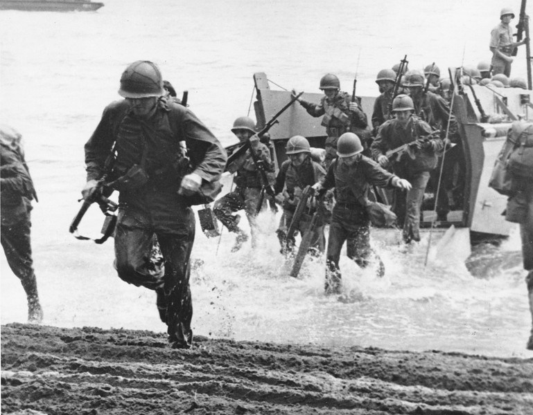 A group of U.S. Marines running through water with determination.