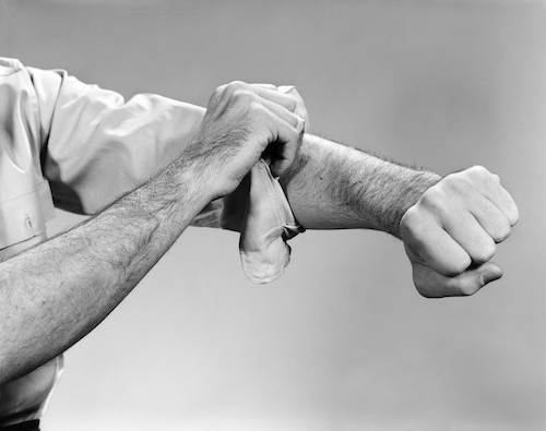 A man in a black and white photo is seen putting a bandage on his arm.