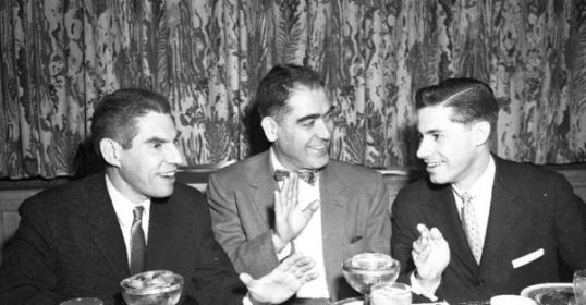 Three men in suits sitting at a dinner table.