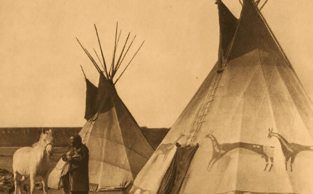 A man standing next to a teepee.