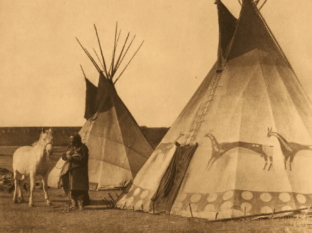 A man standing next to a teepee.