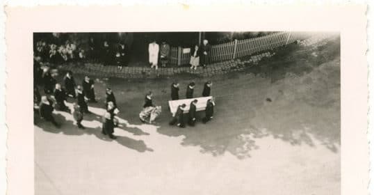 A black and white photo of a funeral procession captures a solemn moment.