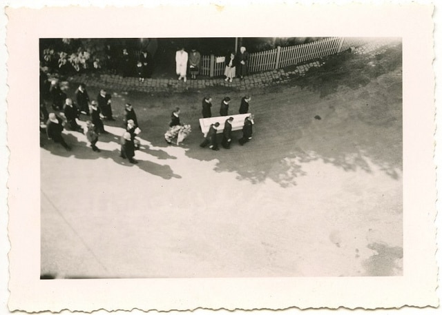 A black and white photo of a funeral procession captures a solemn moment.