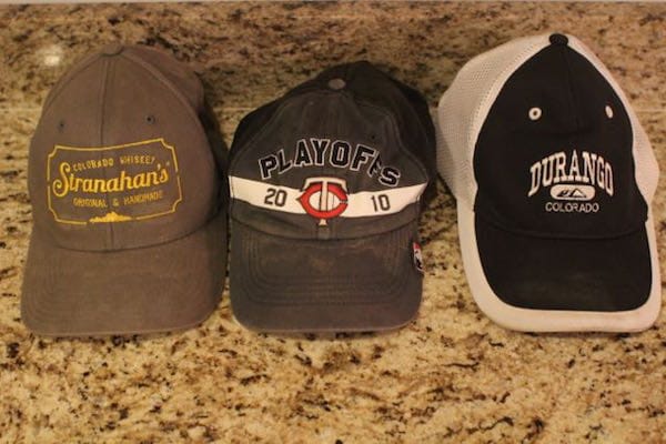 Three clean baseball caps on a counter top.