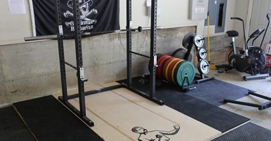 A gym with a squat rack and other weightlifting equipment.