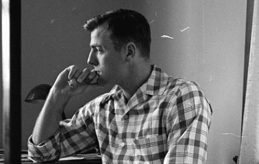 In a moment of reflection, a man sits at his desk puffing on a cigarette as he contemplates life's challenges.