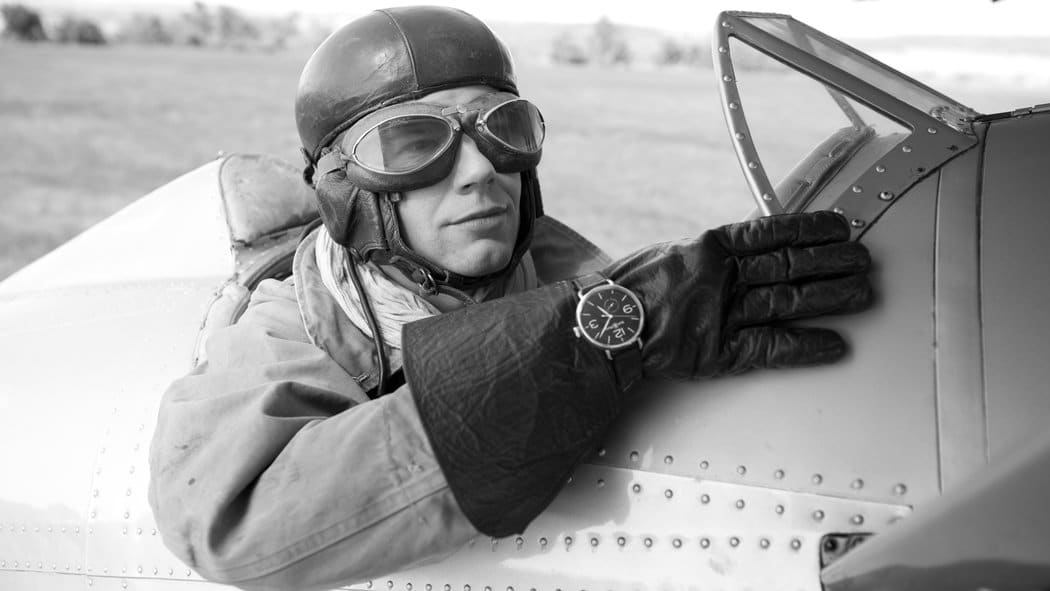 Vintage pilot wearing aviator's watch outside leather gloves.