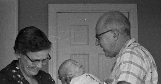 A black and white photo of a grandmother holding a baby.