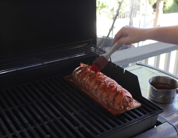 Grilling and brush with sauce on grill and cedar plank.