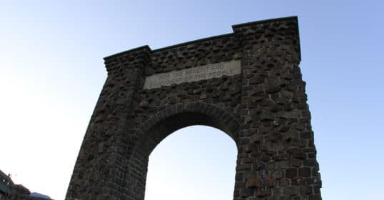 A large stone arch with a sign.