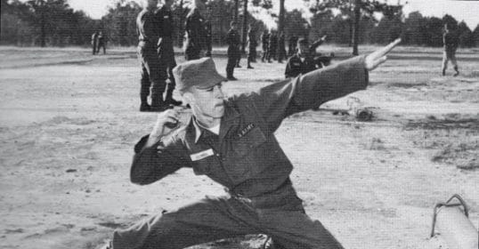 An old photo of a man in combat uniform with a gun.