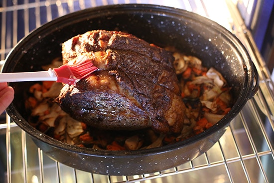 Brushing prime rib roast with marinade while cooking.