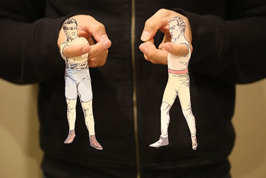 A man doing finger puppets of two boxers at new york world magazine. 
