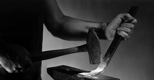 A blacksmith tirelessly hammering a piece of metal on an anvil.