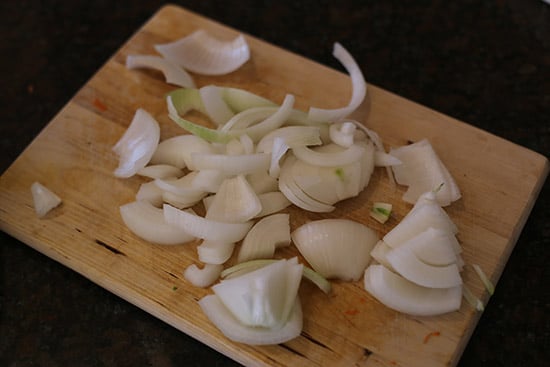 Raw chopped onions on a wooden cutting board.