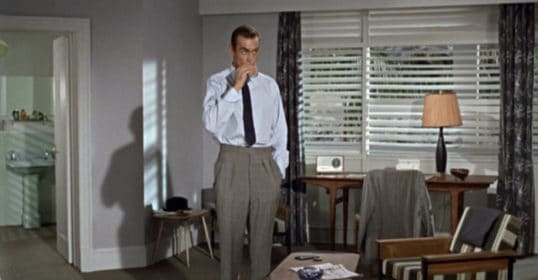 A man in a suit standing in a stylish living room.