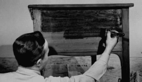 A man is finishing wood with a brush.