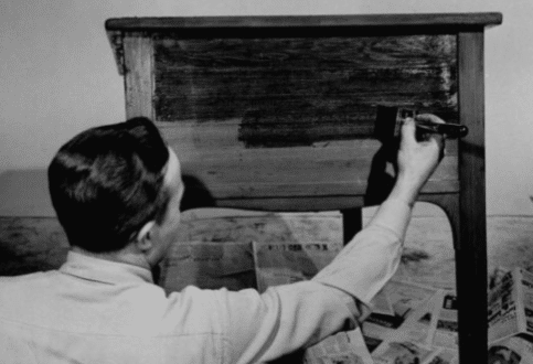 A man is finishing wood with a brush.