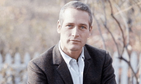 A casual man sits on a bench with his arms crossed.