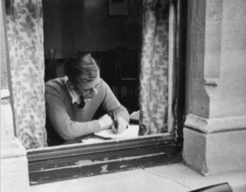 A man in a window, twenty-one old, writing.
