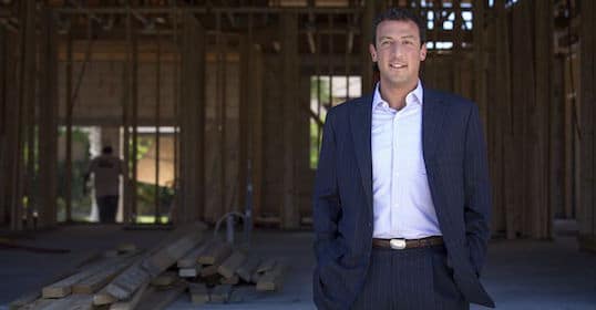 A man in a suit, blind entrepreneur Isaac Lidsky, stands in an unfinished house.