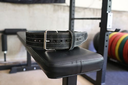 Black leather weightlifting belt on a bench.