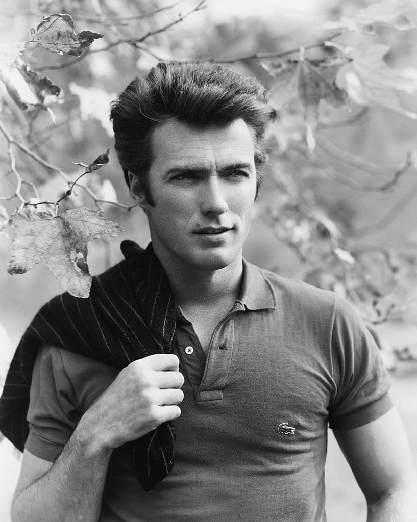 Clint Eastwood cổ điển mặc áo polo với ánh mắt xa rời trên vai cùng áo khoác.