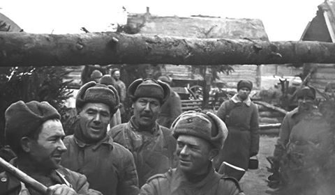 A group of men are cooking food in a pan.