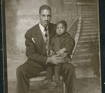 A man and a child sit on a chair, portraying a heartwarming fatherly moment.